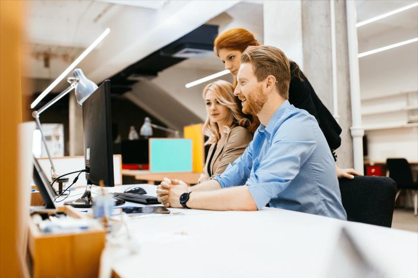 Staff sitting by computer, collaborating using SharePoint features and tools at a workplace